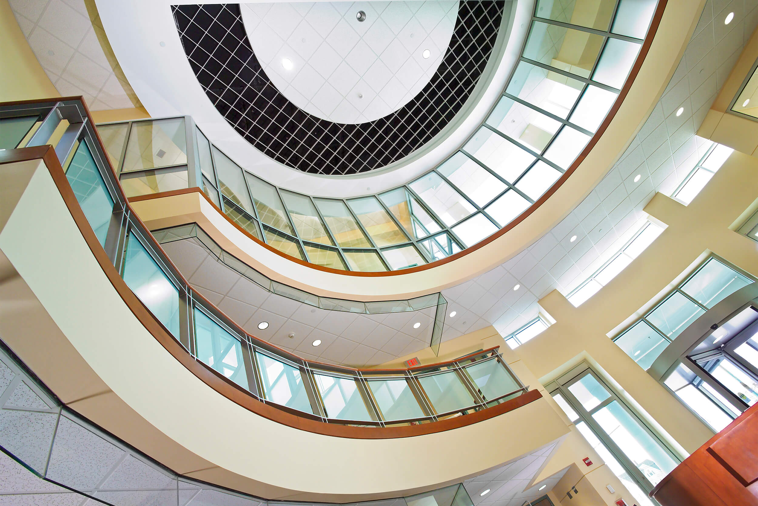 Upwards angled interior view of the atrium lobby at a medical center. Multiple floors can be seen with glass balcony barriers.